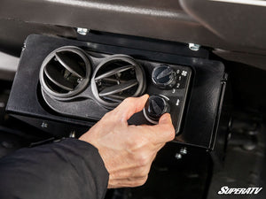Rider adjusting the fan control on a SuperATV second-row heater in a Can-Am Defender MAX